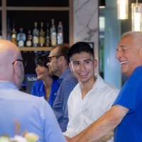 3 men smiling around a table